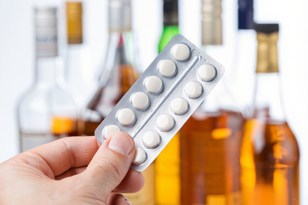 Блистер таблеток на фоне бутылок